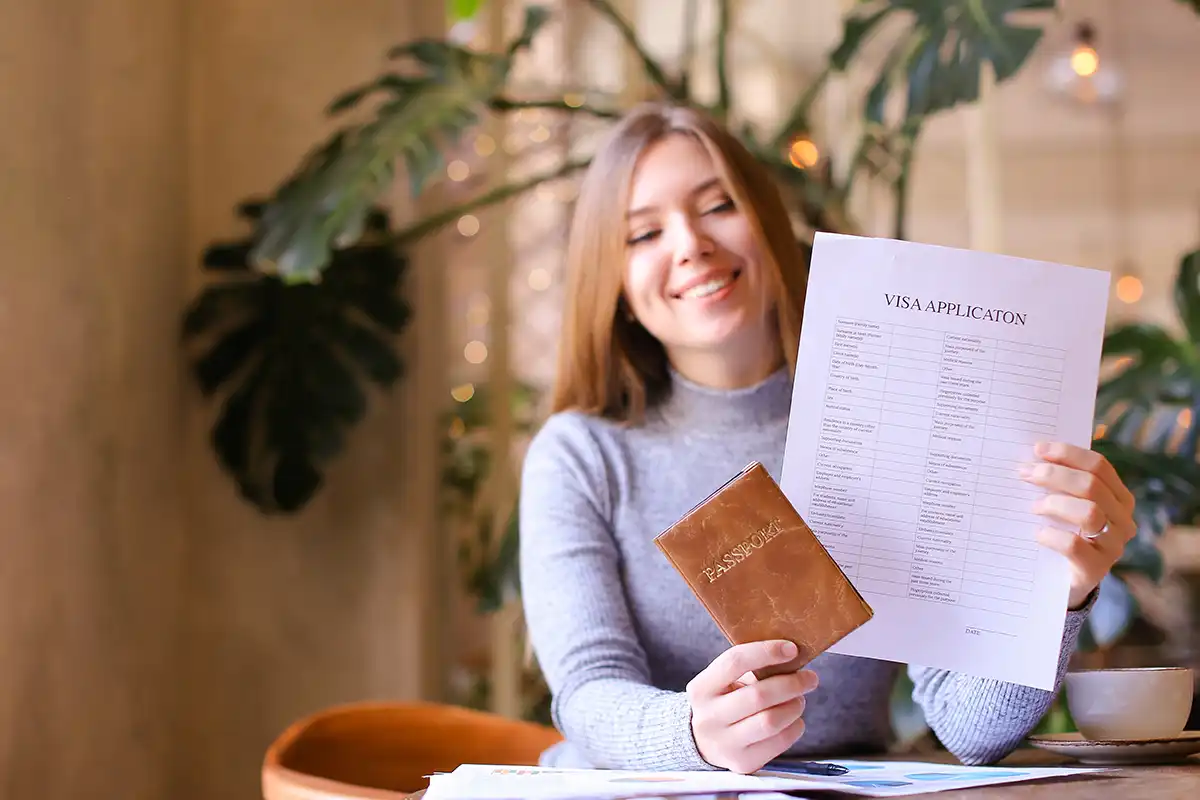 Young girl holding passport and visa application, sitting at cabinet.